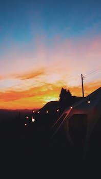 宁静的露营地笼罩在色彩鲜艳的美丽日落中，营地设有帐篷，背靠山脉