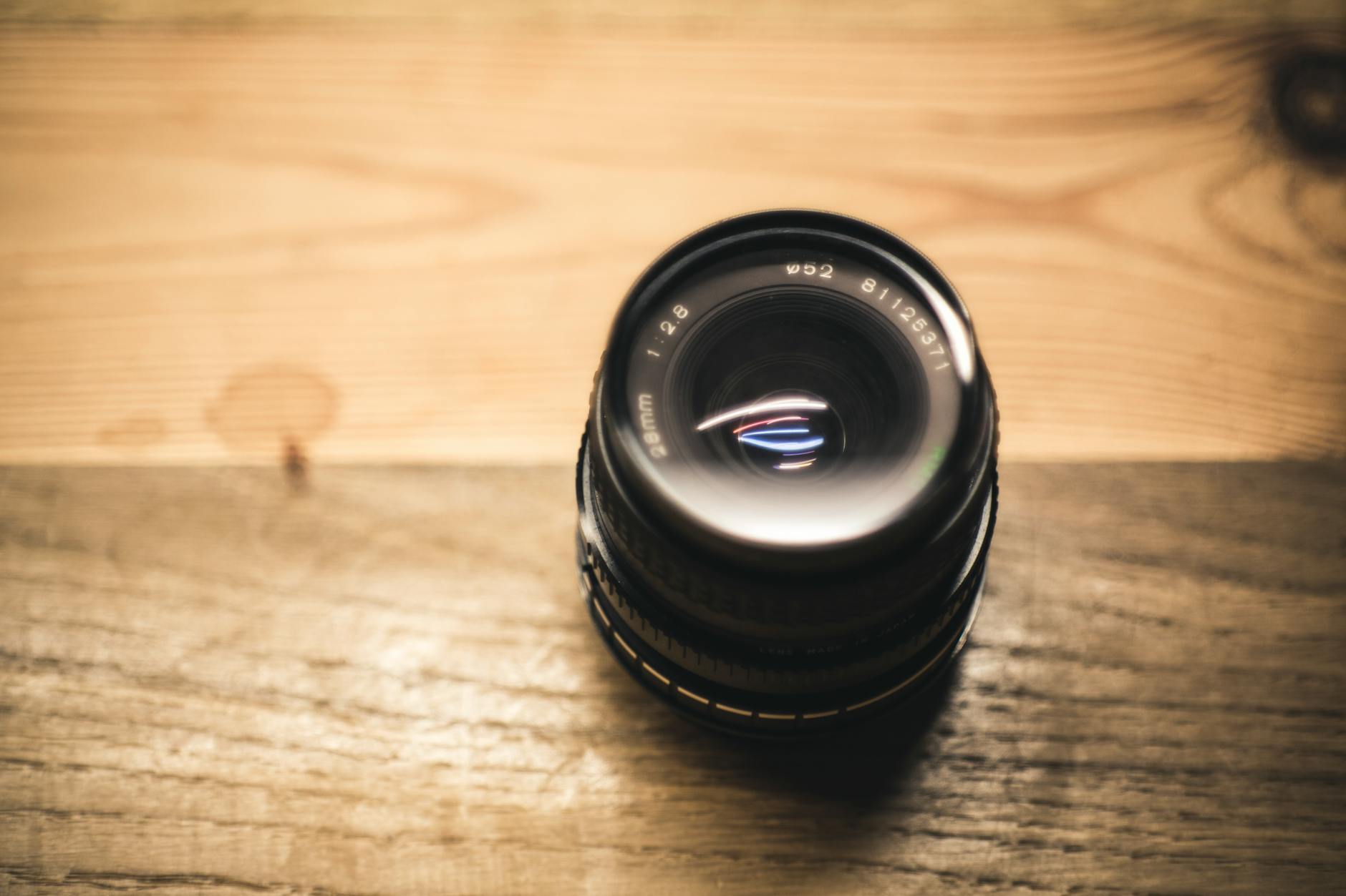 Detailed shot of a camera lens resting on a wooden table