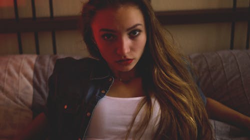 Woman in Blue Denim and White Shirt Sitting Inside Brown Painted Room