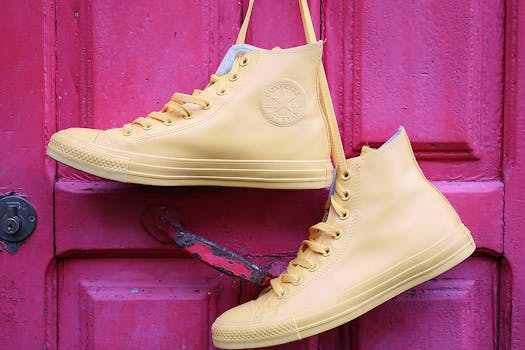 Stylish yellow high-top sneakers hanging on a vibrant pink painted door.