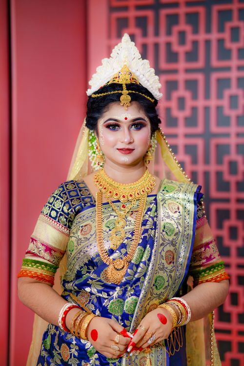 Free A South Asian woman in vibrant traditional attire with intricate jewelry poses elegantly indoors. Stock Photo