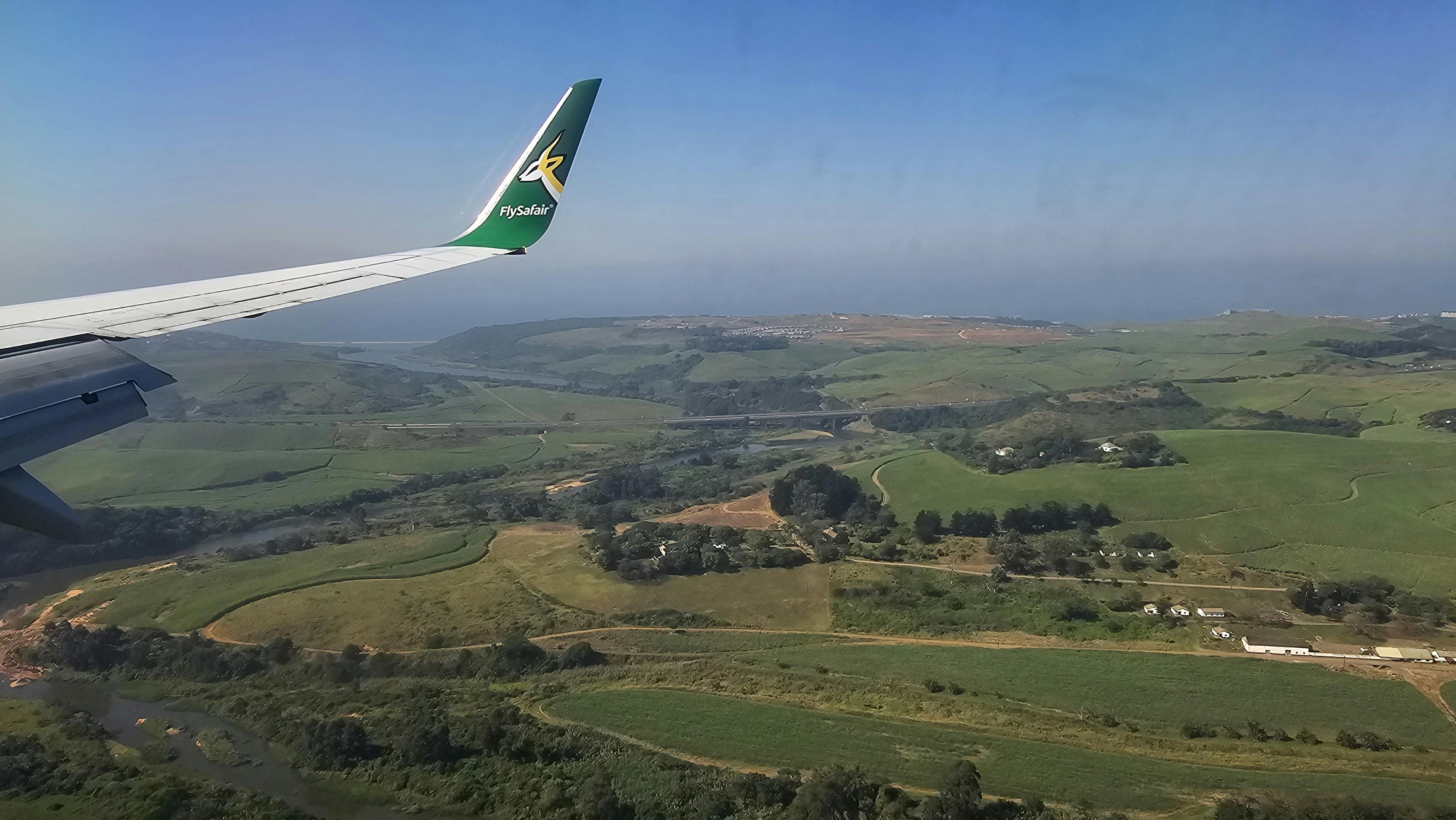 Breathtaking aerial view of lush green fields from an airplane with visible wing.