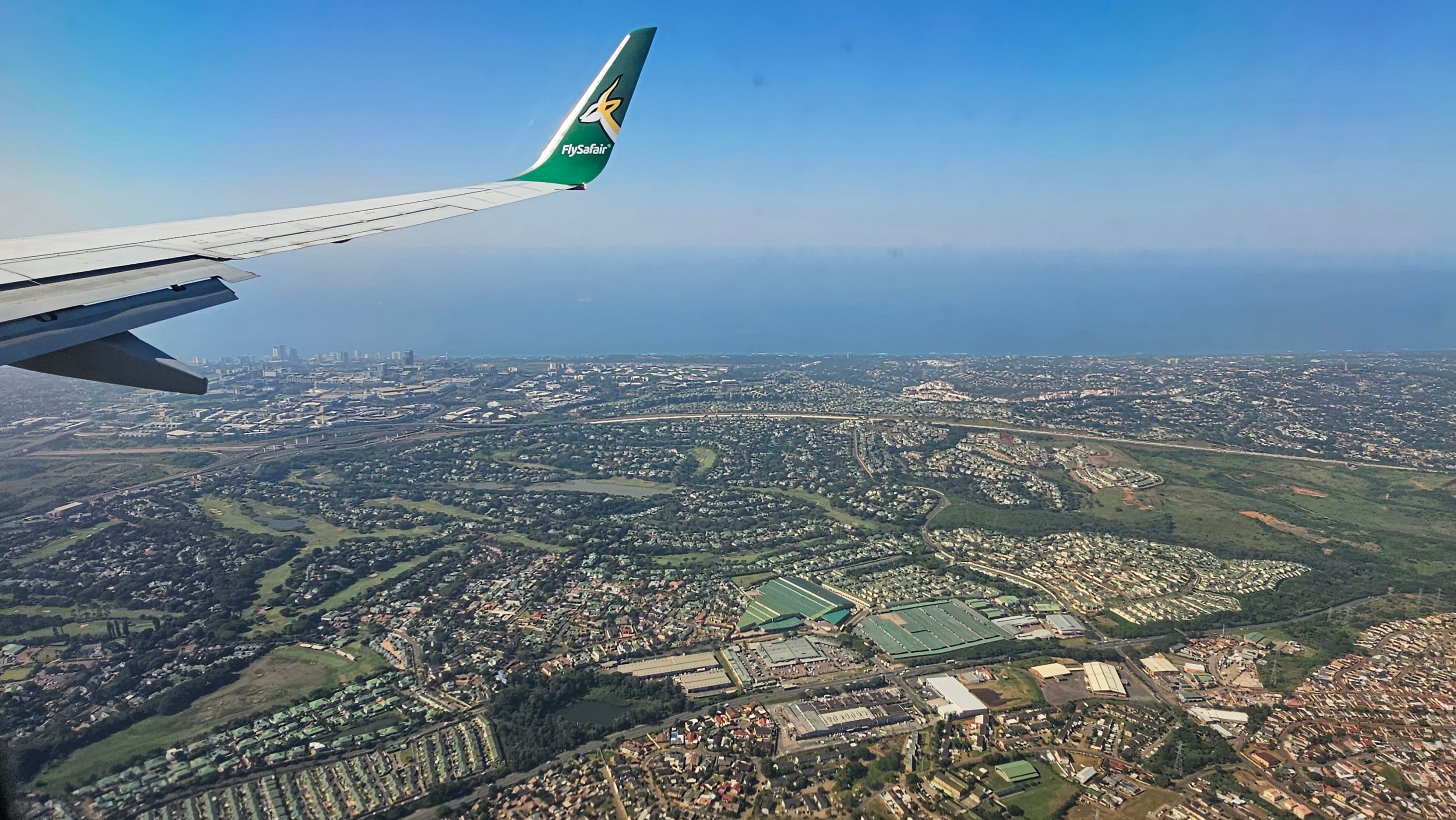Capture of cityscape from airplane with FlySafair wing visible.