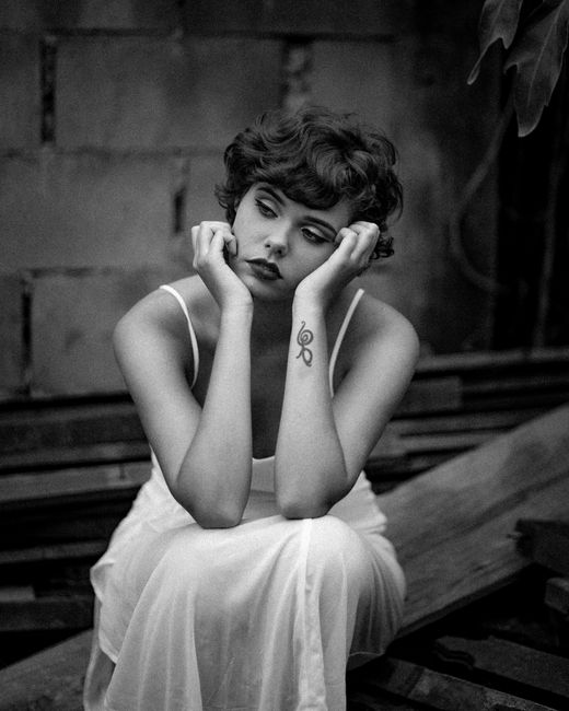 Black and white portrait of a young woman deep in thought, sitting alone.