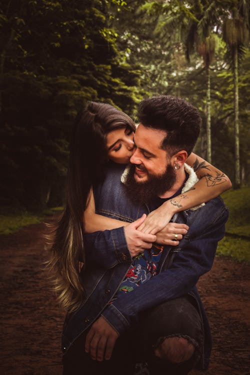 Woman Back Hugging and Kissing Man in Forest