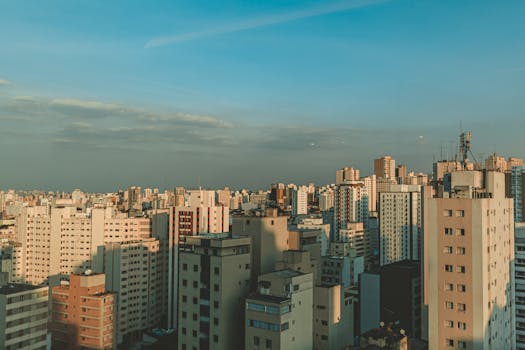 黄昏时分，从空中俯瞰，密集的城市天际线中矗立着现代化的摩天大楼，天空晴朗