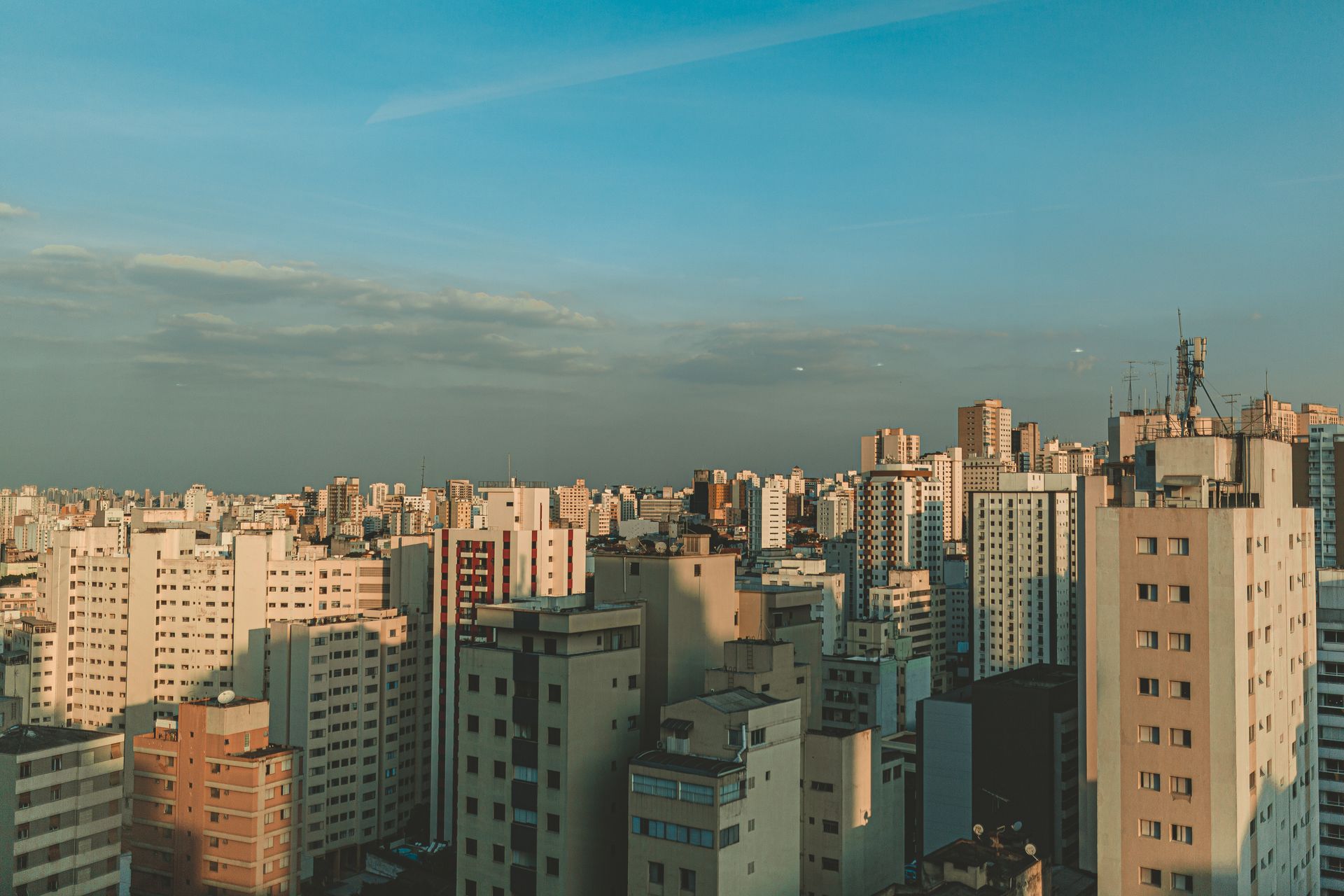Aerial view of a dense city skyline at dusk with modern skyscrapers and a clear sky.