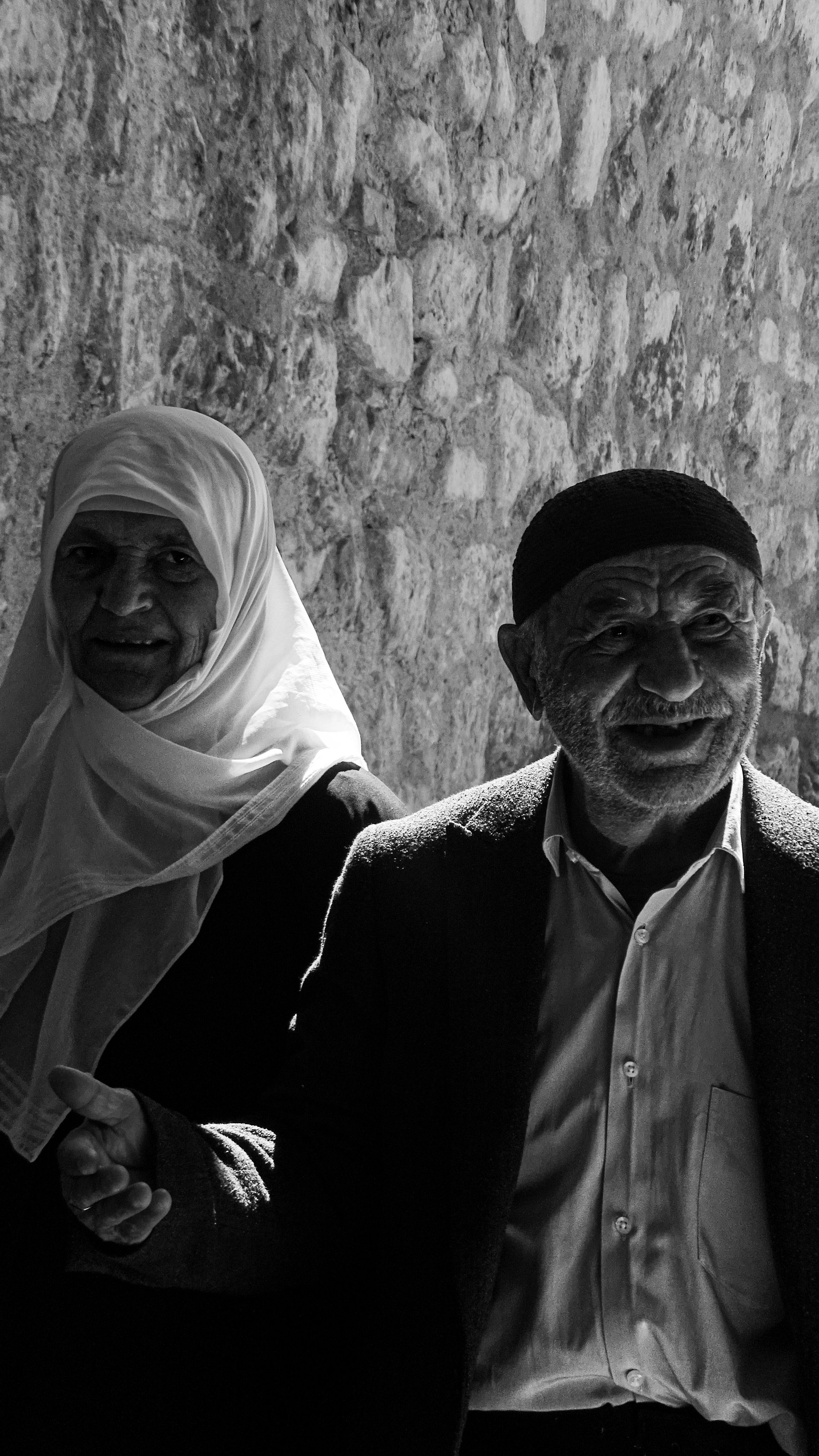 Black and white portrait of a smiling elderly couple walking in an Istanbul street.