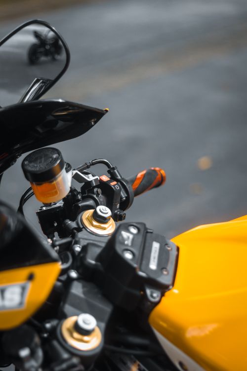 Free Detailed view of a yellow motorcycle handlebar with selective focus, showcasing modern design. Stock Photo