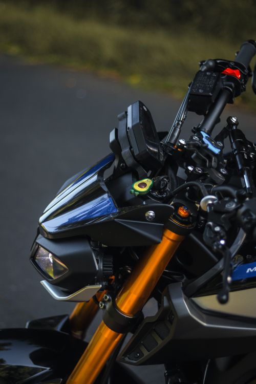 Free Detailed view of a motorcycle front with handlebars on a road, showcasing modern design. Stock Photo
