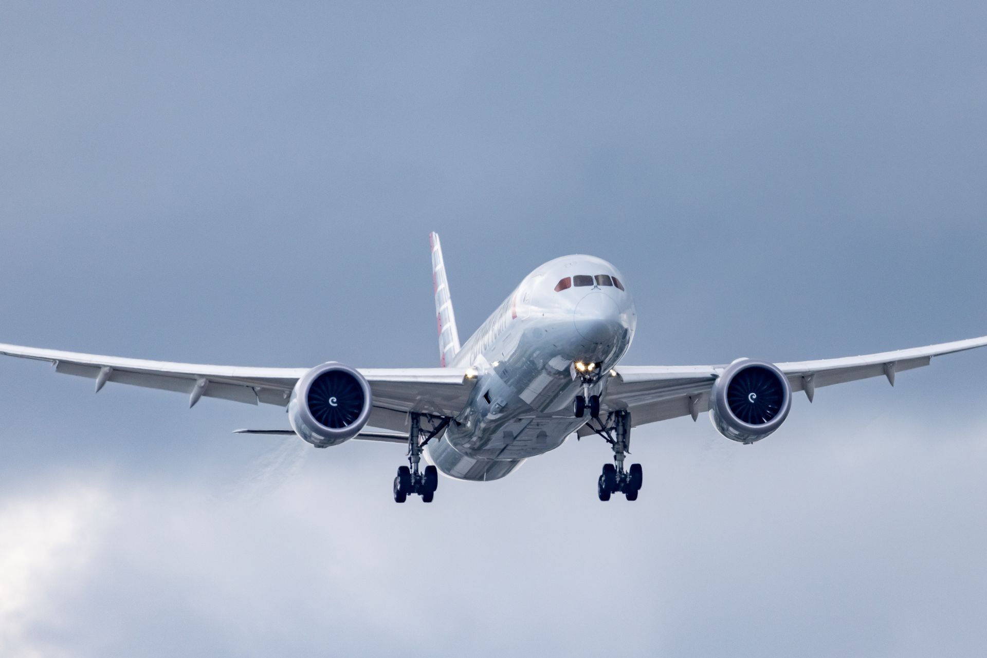 American Airlines widebody jet on final approach against a cloudy sky