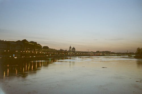 A river with buildings in the background at sunset