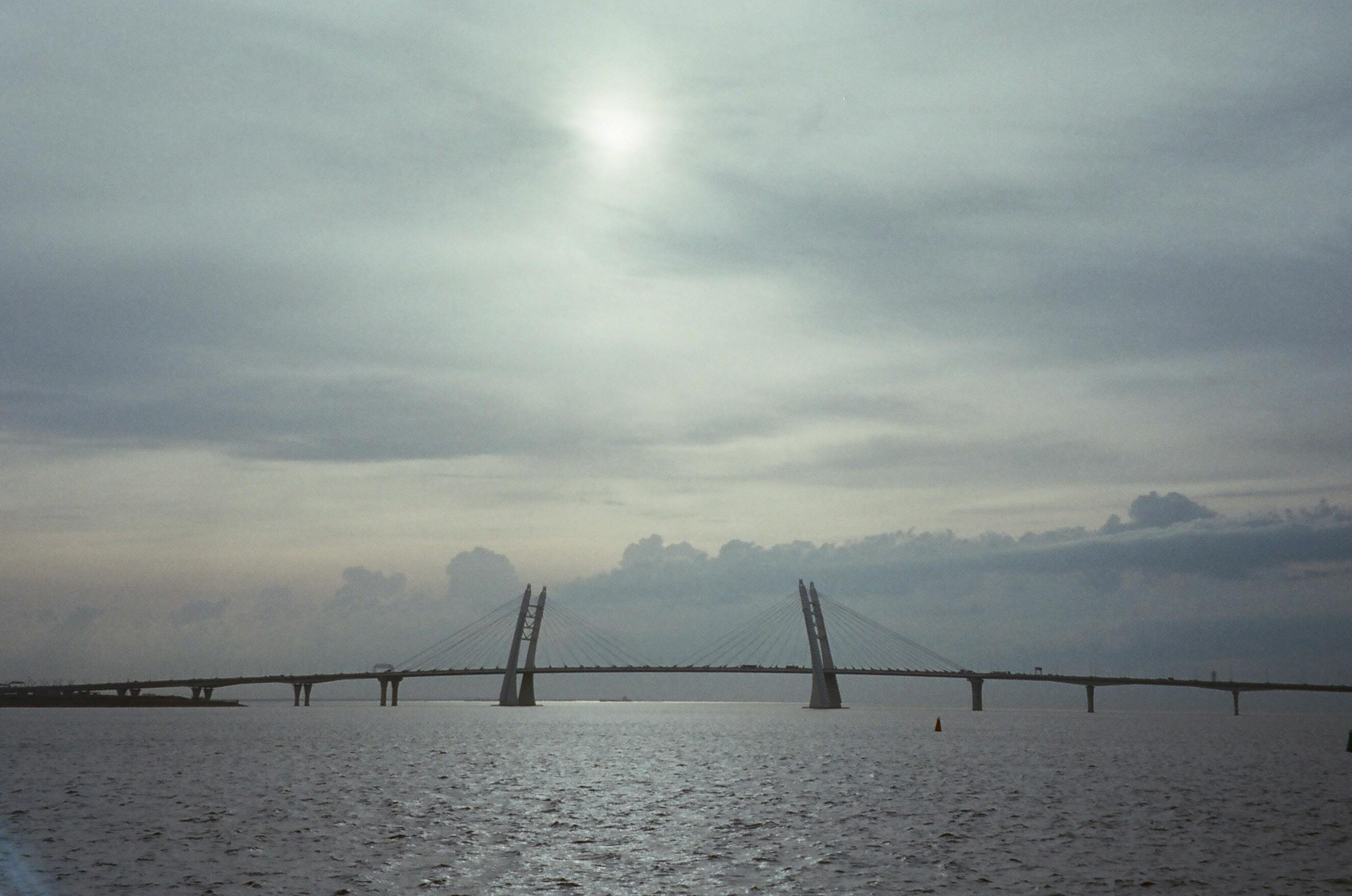 Dramatic dusk view of a cable-stayed bridge spanning across a tranquil river.