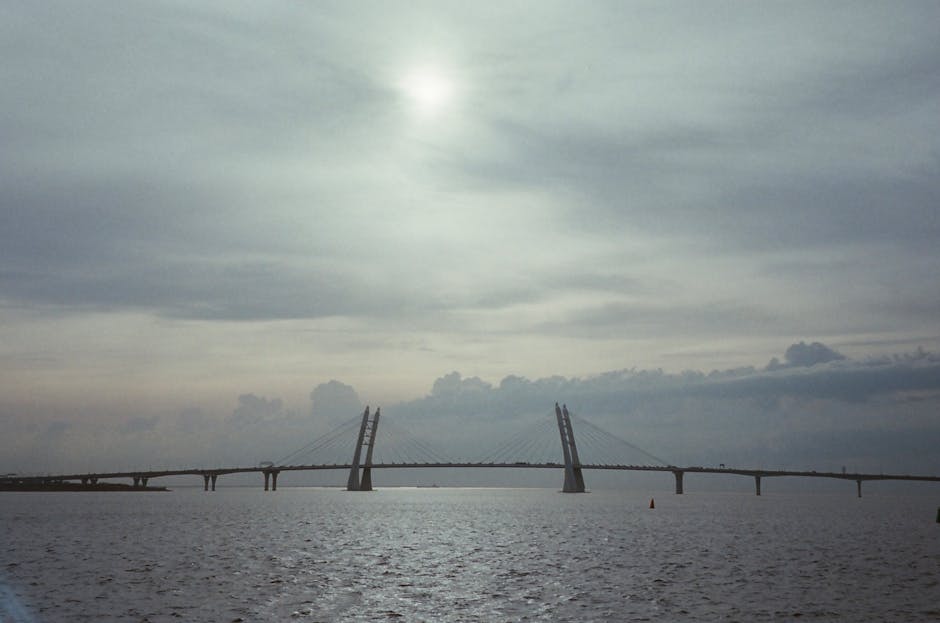 Dramatic dusk view of a cable-stayed bridge spanning across a tranquil river.