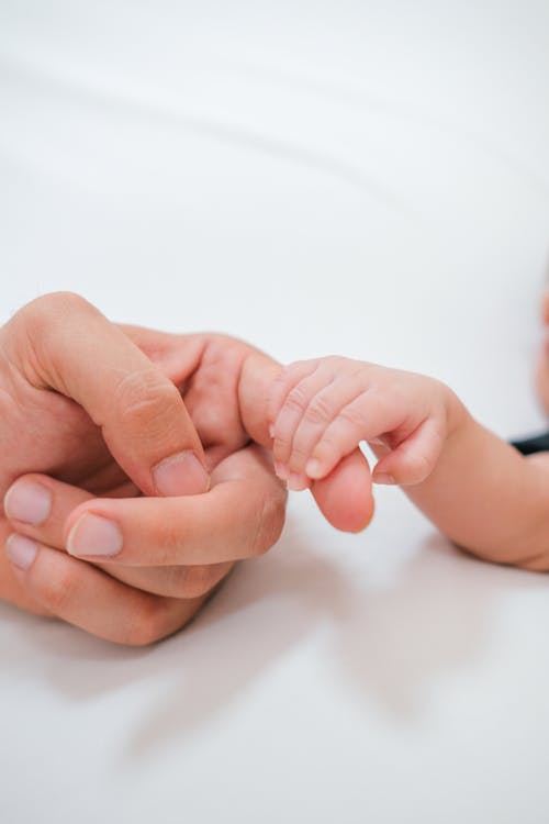 A baby's hand is held by a man's hand