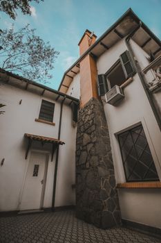 Beautiful facade of a house with a prominent stone chimney and antique window design.