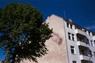 晴朗的蓝天下，低角度拍摄着柏林一栋现代化公寓楼和郁郁葱葱的树木