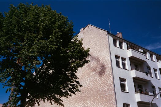 晴朗的蓝天下，低角度拍摄着柏林一栋现代化公寓楼和郁郁葱葱的树木