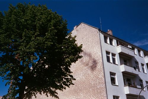 Free Low angle view of a modern apartment building and lush tree in Berlin, Germany, under a clear blue sky. Stock Photo