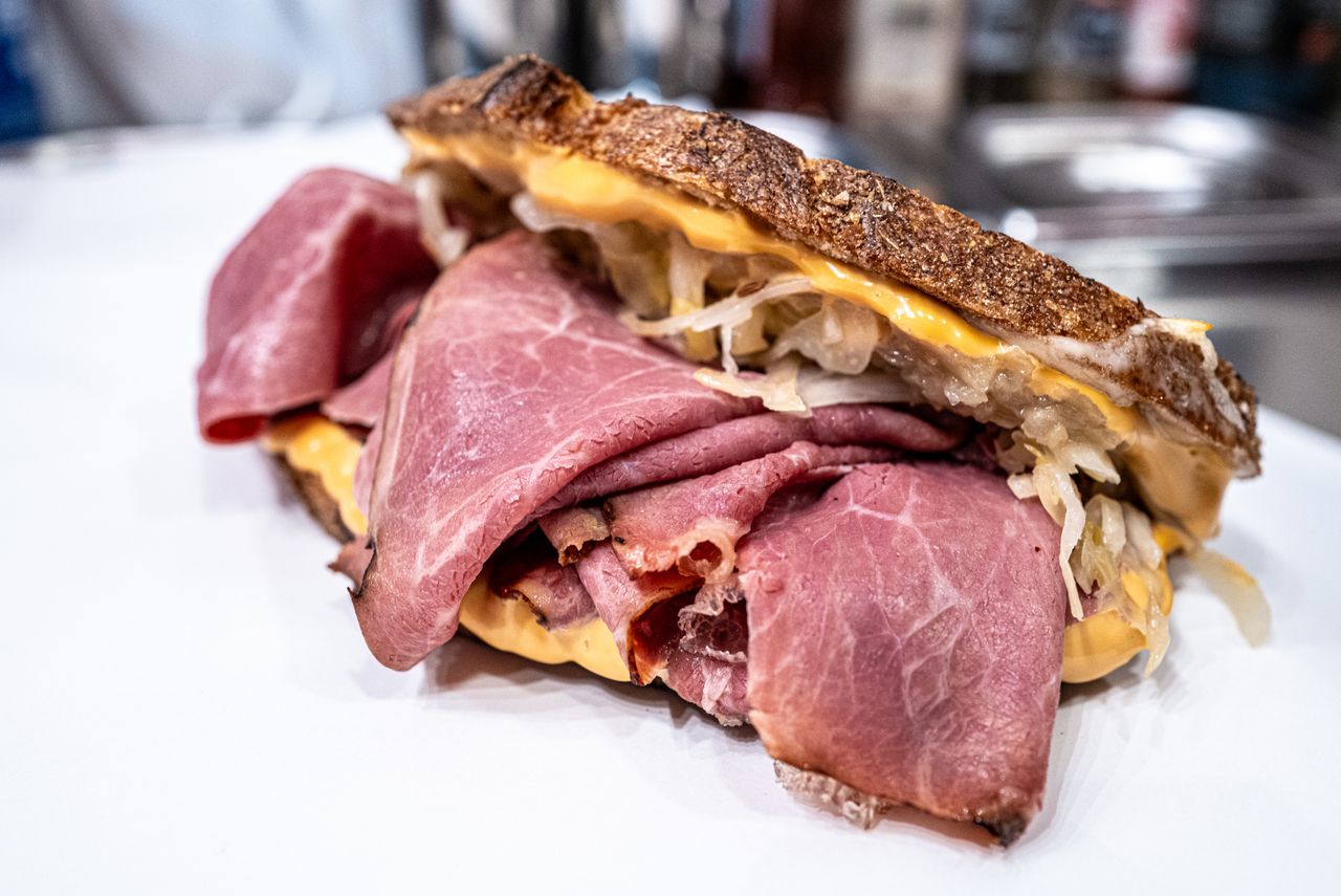 Reuben-style sandwich with corned beef, melted cheese, and sauerkraut on rustic rye bread