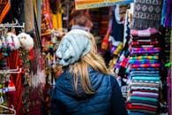 A woman walking through a market with colorful items