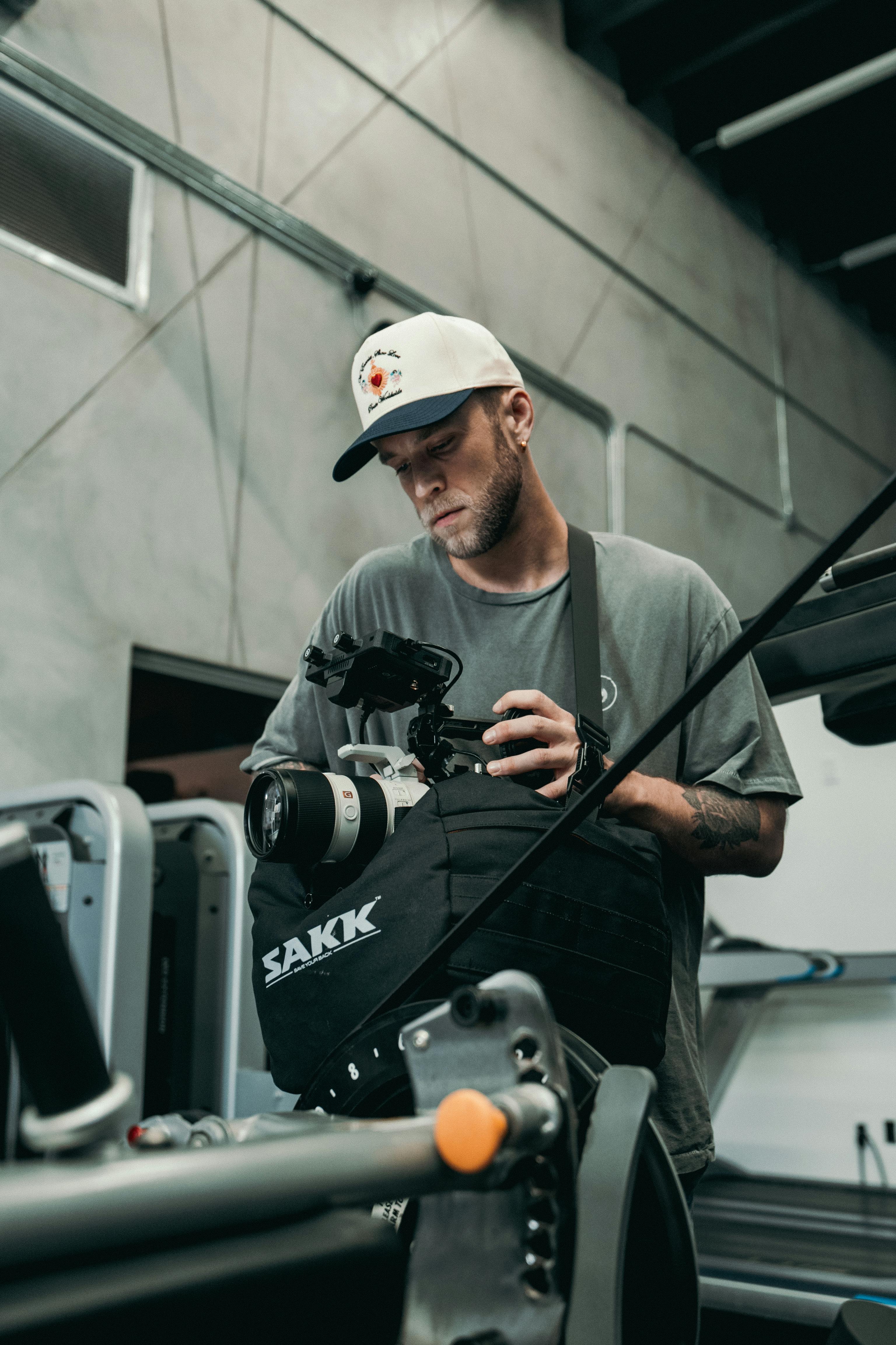 a man in a hat and a white shirt holding a camera