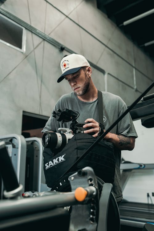 A man in a hat and a white shirt holding a camera