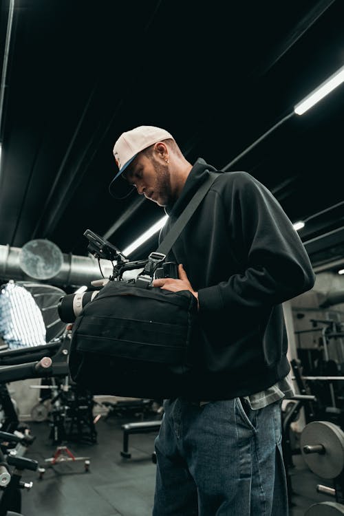 A man holding a camera bag in a gym