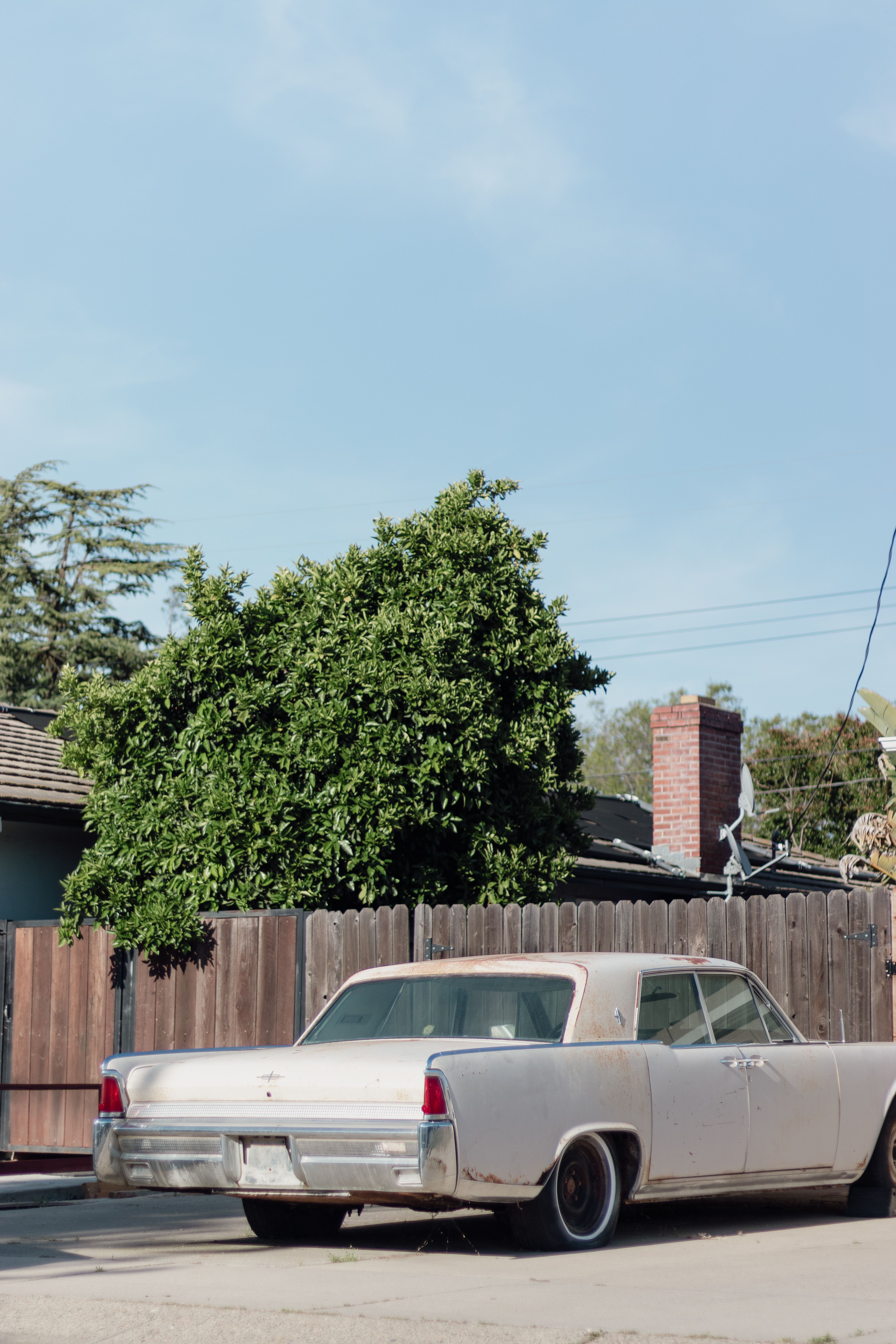 A white car parked in front of a fence · Free Stock Photo