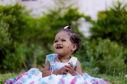 a small sitting in garden and looking side up 