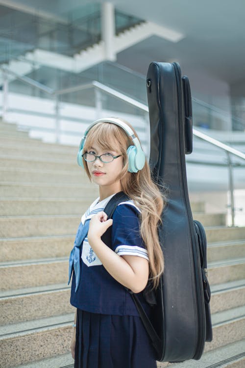 A girl with headphones and a guitar case