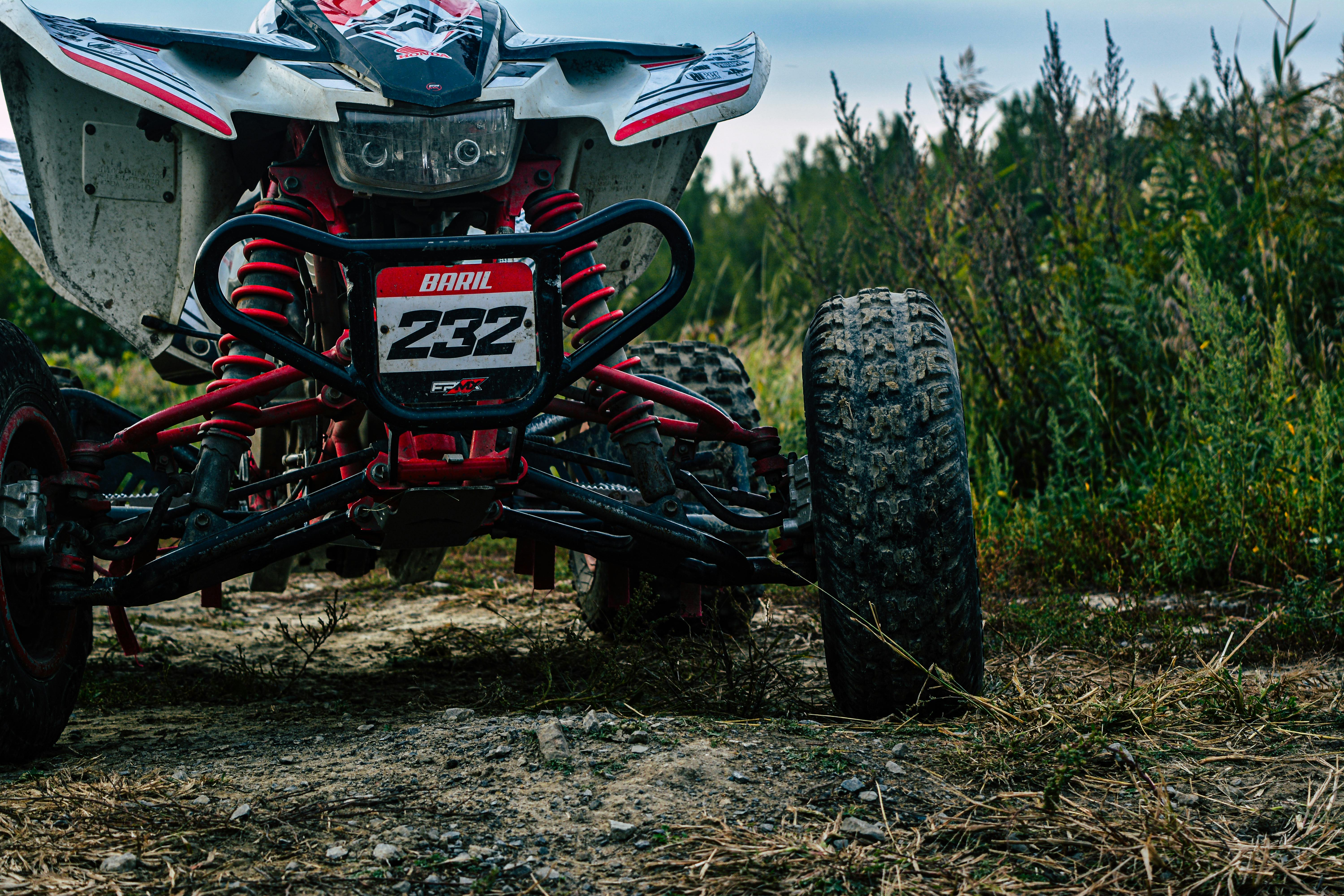 Powerful quad bike on a rugged dirt road amidst lush greenery, ready for an adventurous ride.