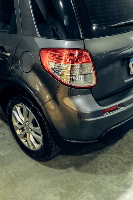 A detailed photo of the back view of a gray Suzuki SX4 car parked in an indoor garage.