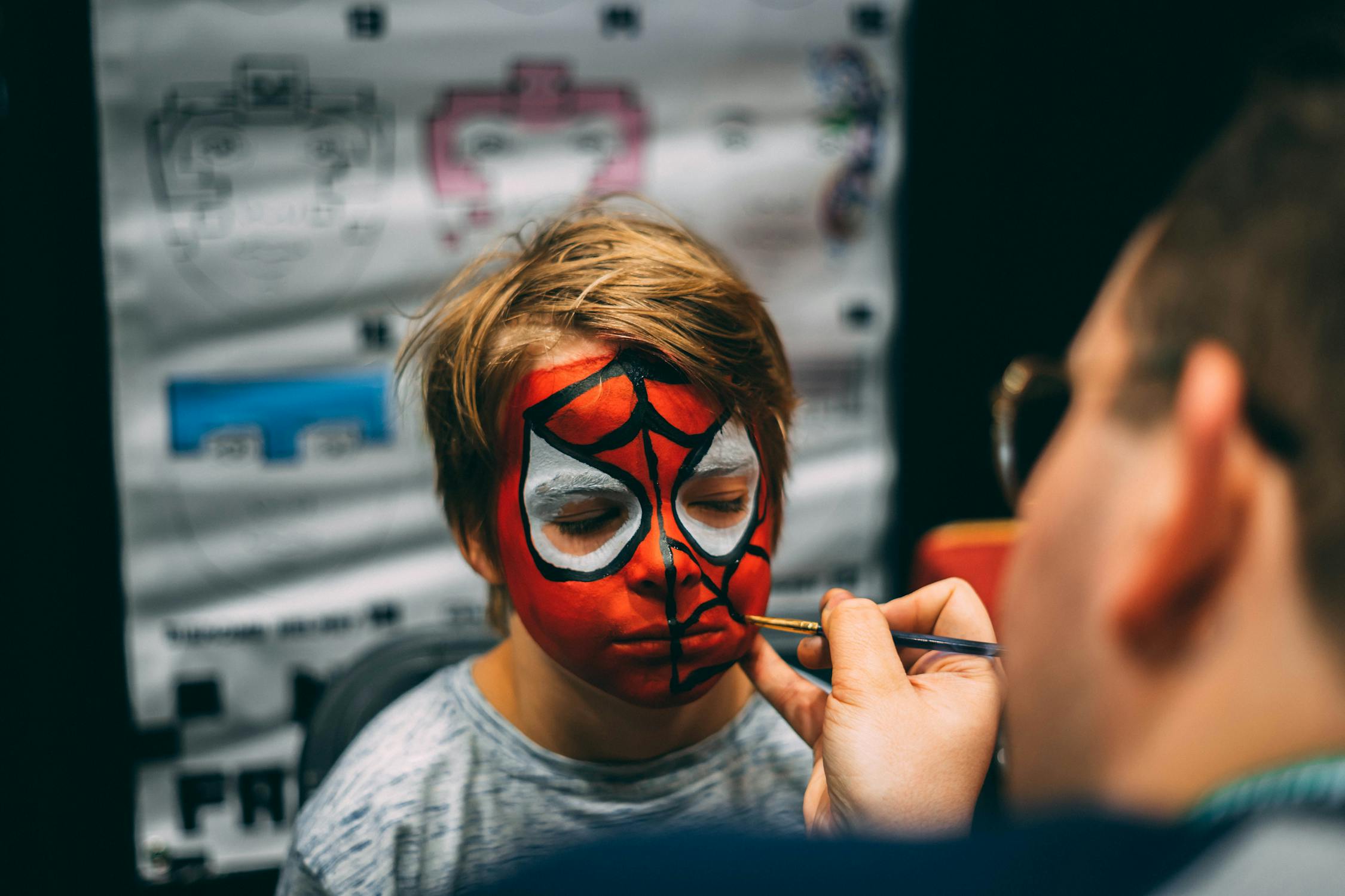 Photo of a child getting their face painted like Spider-Man.