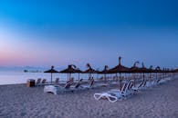 黎明时分，宁静的海滩上摆放着躺椅和棕榈草伞