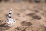沙滩上放置着一只小条纹帆船玩具，背景柔和