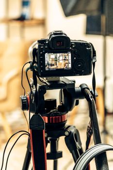 Close-up view of a DSLR camera on a tripod capturing a photography scene indoors.