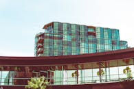 一座现代玻璃建筑映照着绿色植物，将城市建筑与自然融为一体