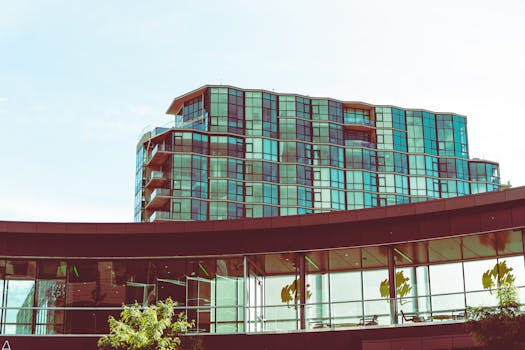 一座现代玻璃建筑映照着绿色植物，将城市建筑与自然融为一体