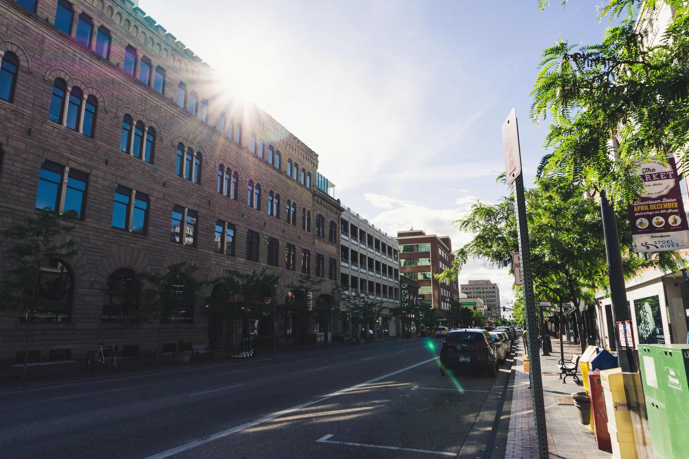 Sunlight peaks over historic buildings in a vibrant downtown street setting.