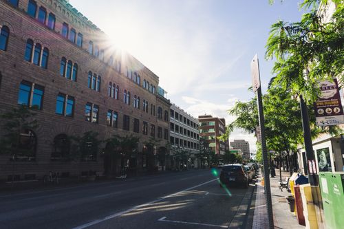Free Sunlight peaks over historic buildings in a vibrant downtown street setting. Stock Photo