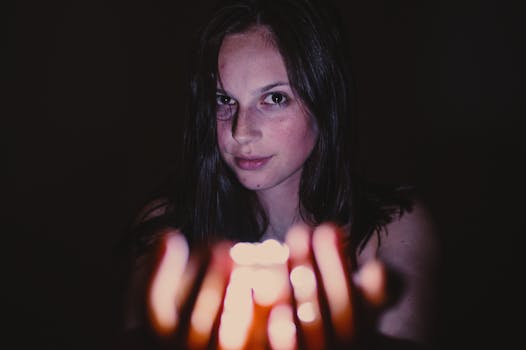 黑暗环境中，一名年轻女子手持发光蜡烛，营造出神秘的氛围