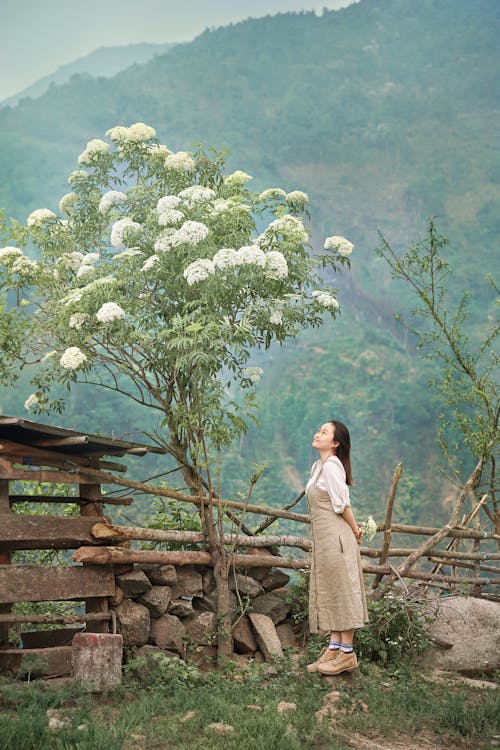 A woman standing in front of a tree with flowers