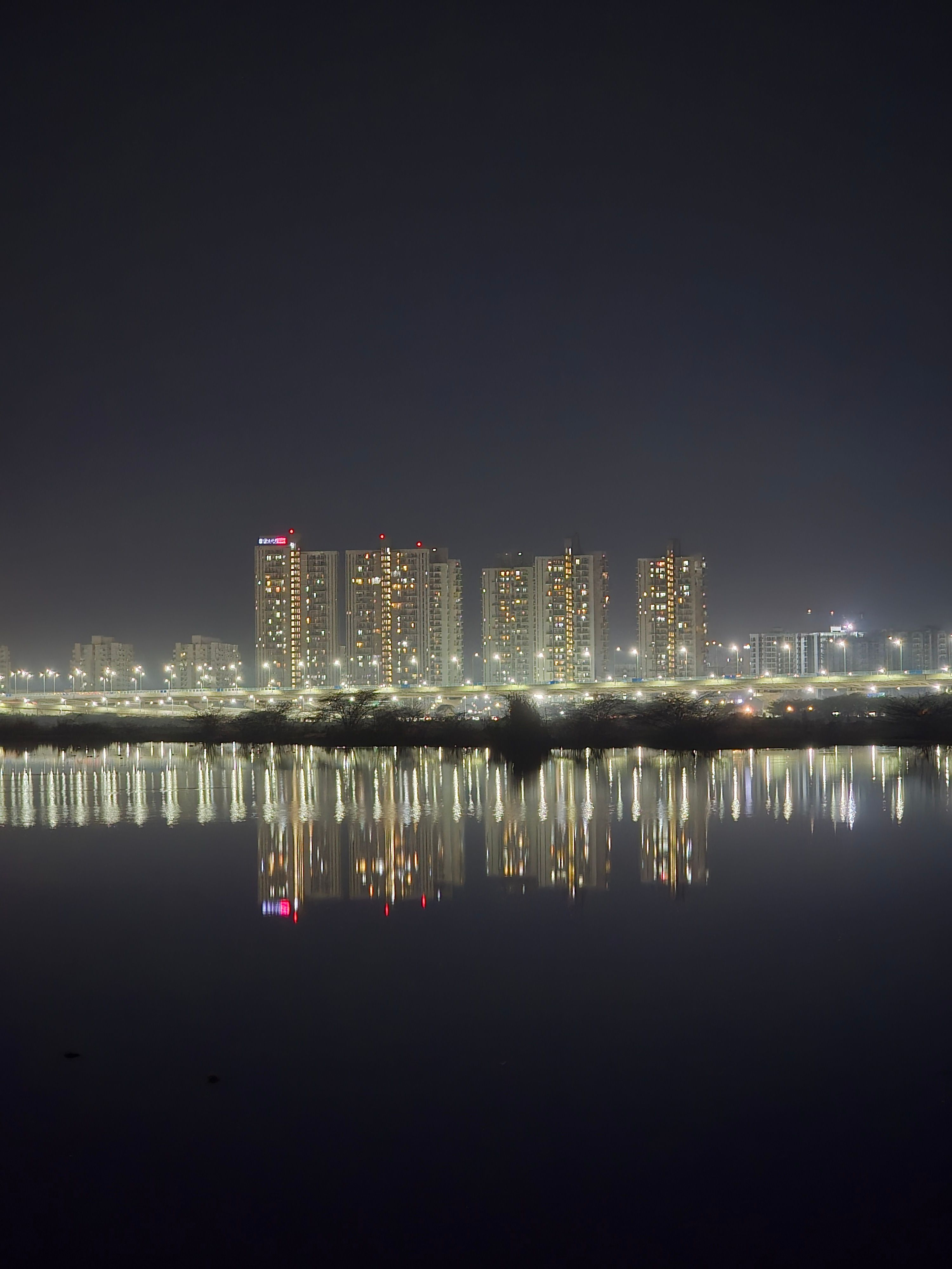 Gurugram skyscrapers illuminated at night, reflected in water