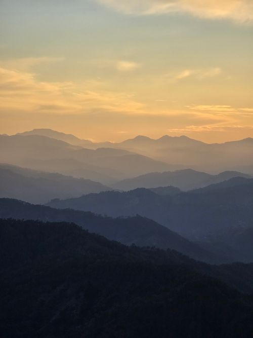 Free Beautiful sunset casting golden light over mist-covered mountains in Kanchula, India. Stock Photo