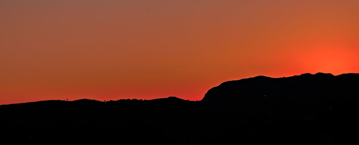 無料 日没時の茶色の空の下の黒い山 写真素材