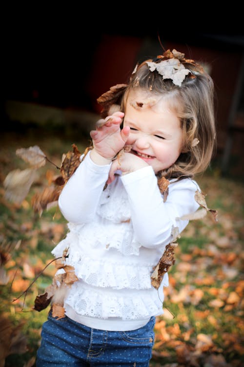 бесплатная Фокус фото девушки в белой рубашке с длинным рукавом с коричневым листом на голове Стоковое фото