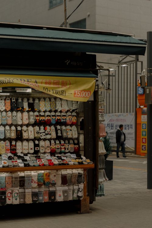Free Urban market stall displaying a colorful variety of socks with signage in an outdoor city setting. Stock Photo