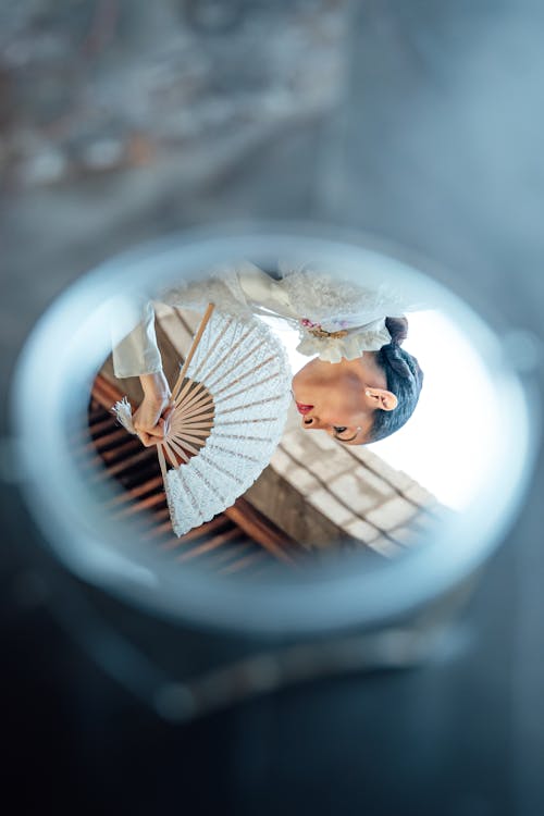 A woman holding a fan in front of a mirror