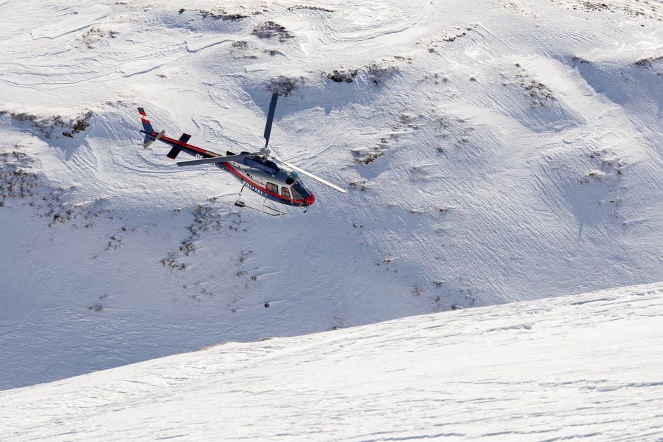 A police helicopter flying over the snow-covered mountains of Heiligenblut, Austria.